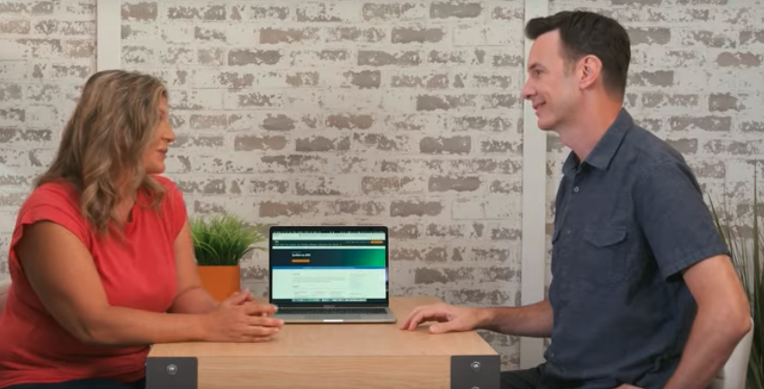 Two coworkers sitting in front of a laptop with an AI both on screen